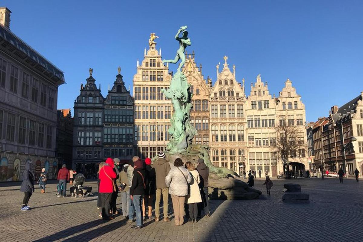 Un grupo de personas de pie alrededor de una estatua en una ciudad.