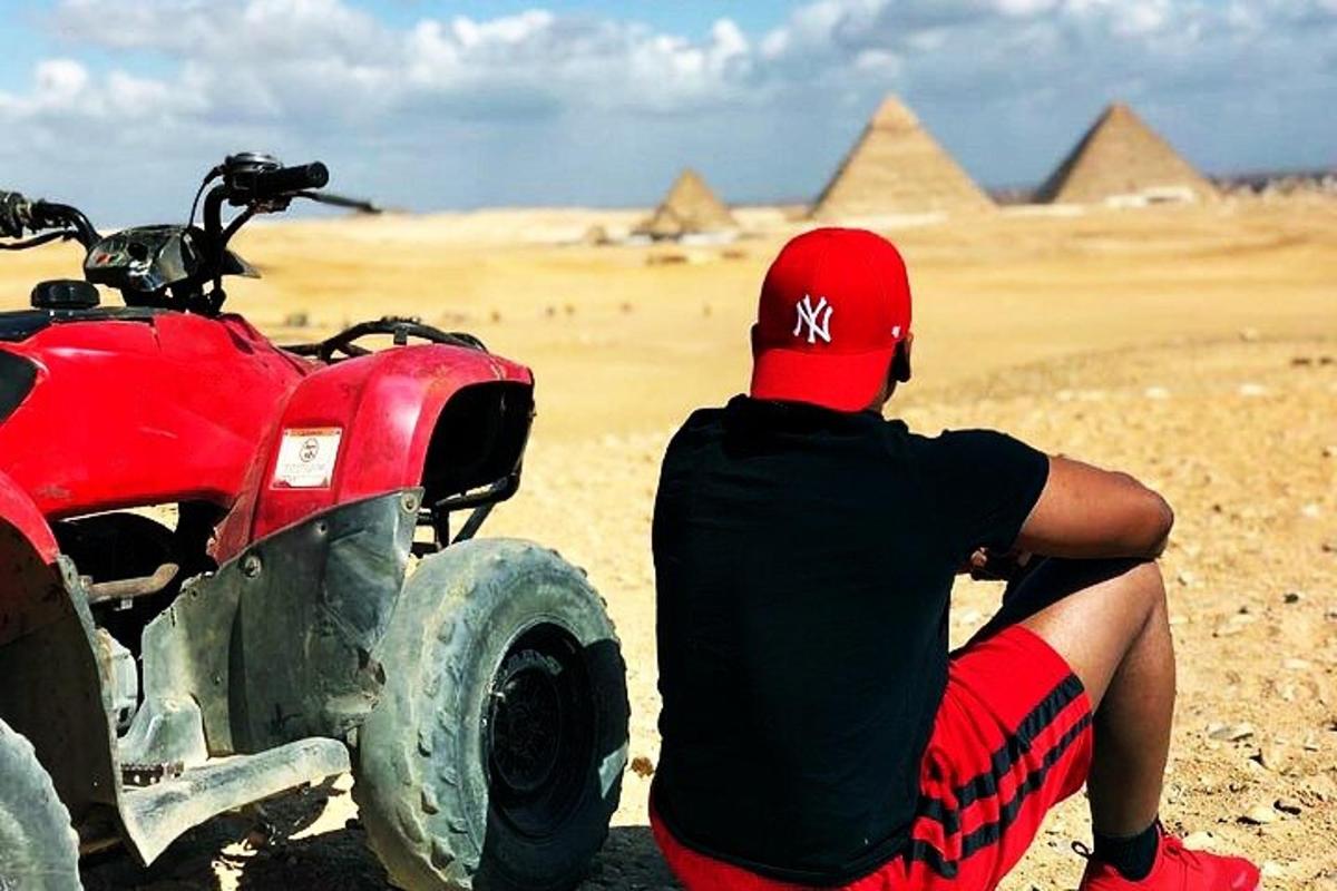 Egy férfi egy piros ATV mellett ül a sivatagban