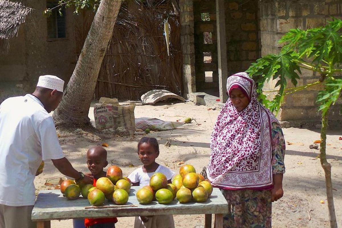 a woman and two children standing next to a table of fruit