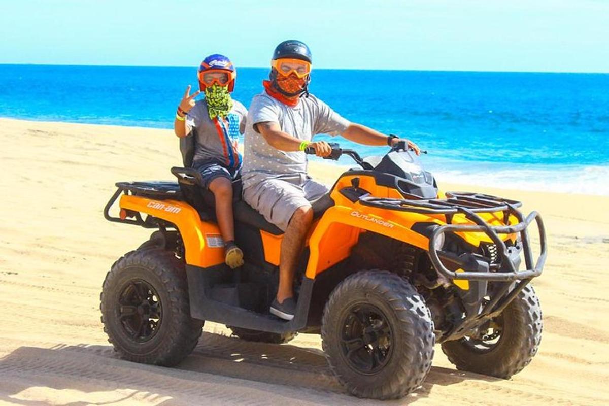 zwei Personen fahren auf einem Quad am Strand