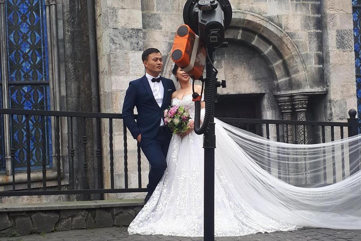 Una novia y un novio de pie junto a una valla