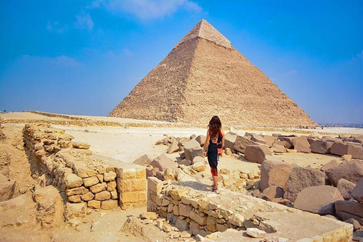 nainen seisoo muurilla pyramidien edessä