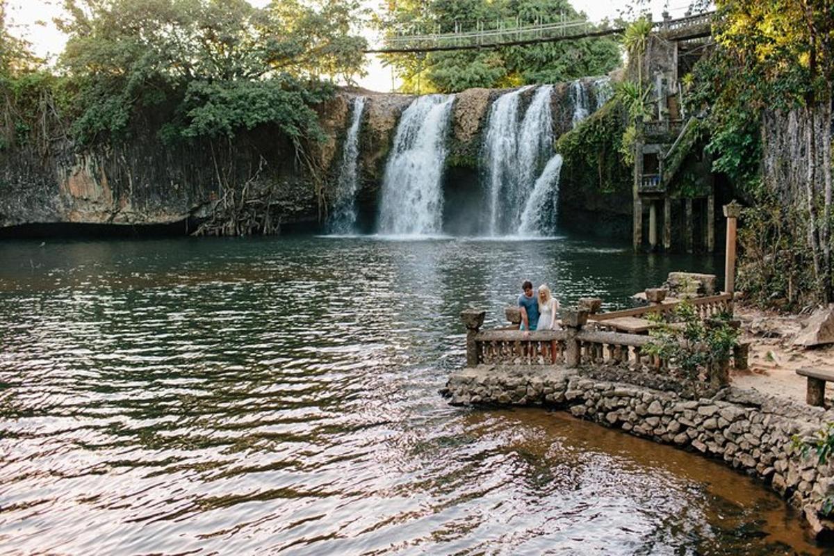 two people sitting on a bench in front of a waterfall