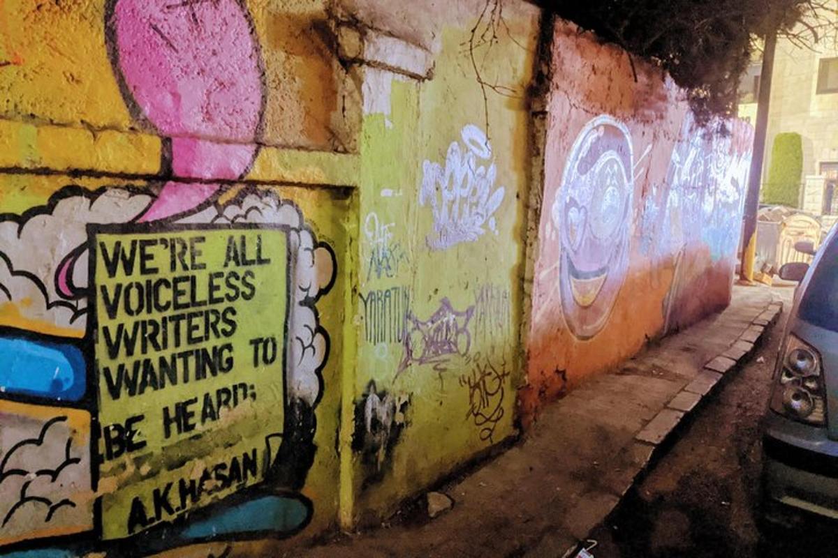 a wall covered in graffiti with a sign on it