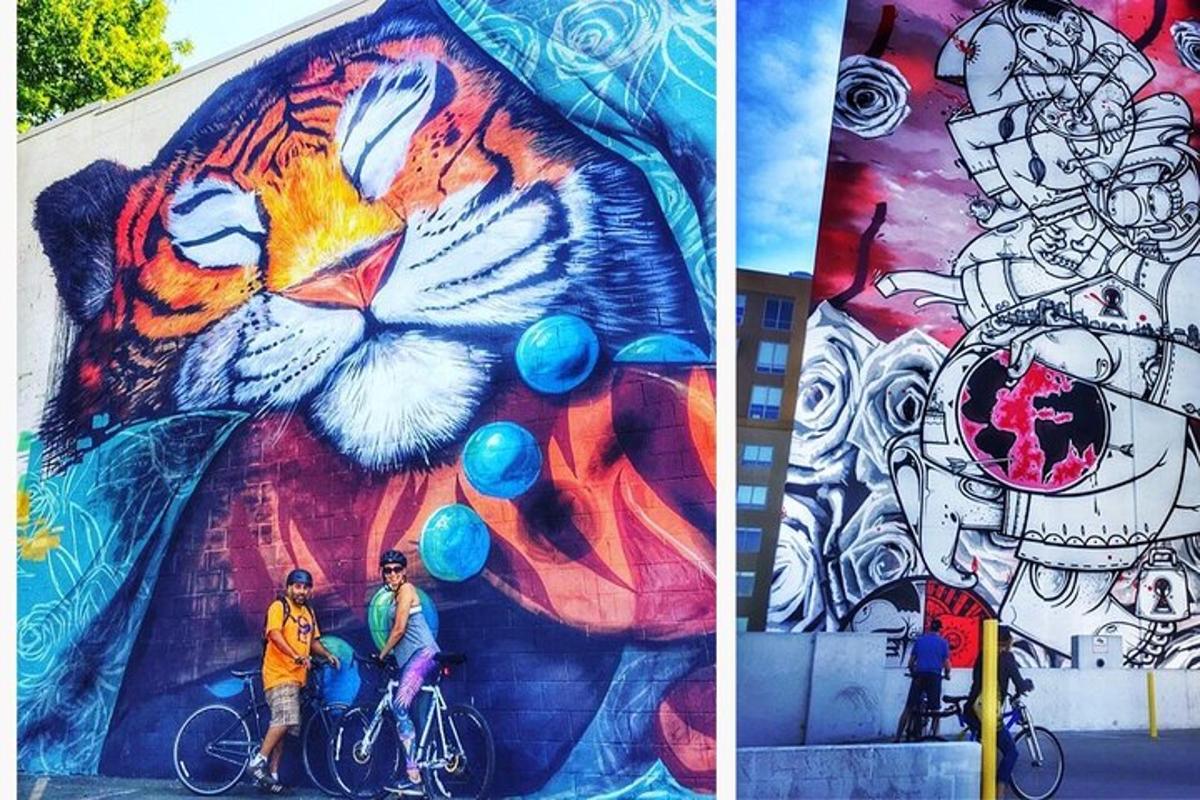 two people on bikes in front of a mural