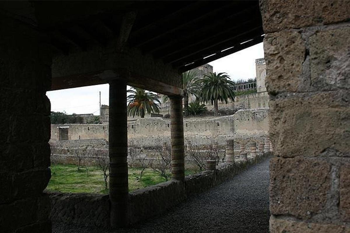 un bâtiment avec un mur de pierre et des palmiers en arrière-plan