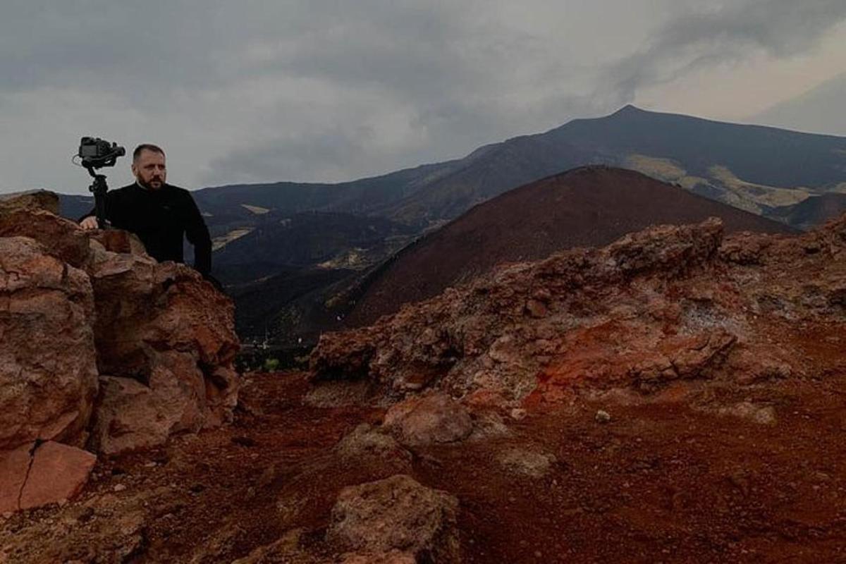 un home dret al cim d'una muntanya amb una càmera