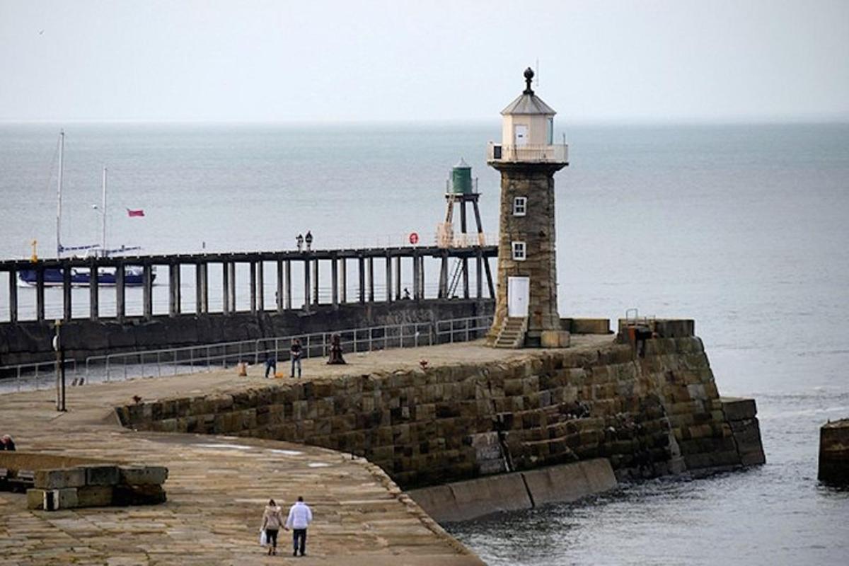 a lighthouse on a pier next to the ocean