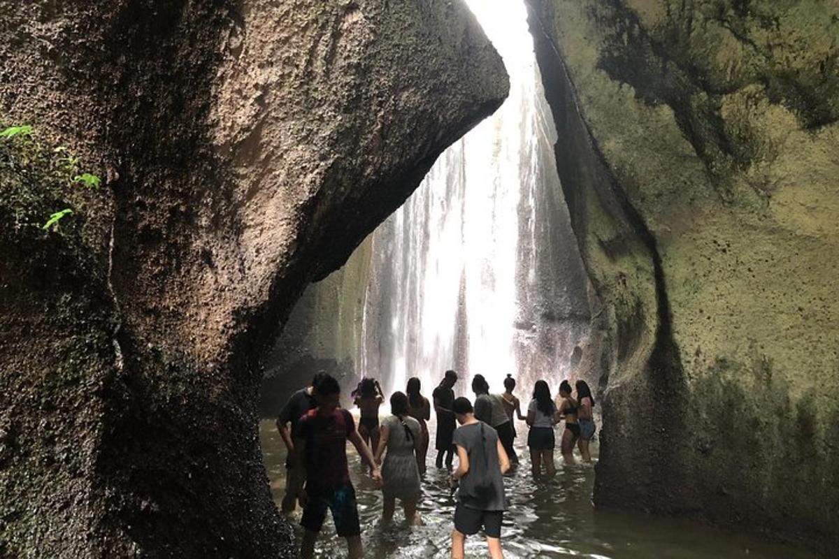 un grup de persones dempeus a l'aigua prop d'una cascada