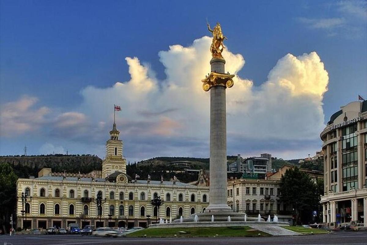 um monumento alto em frente a um prédio com uma estátua