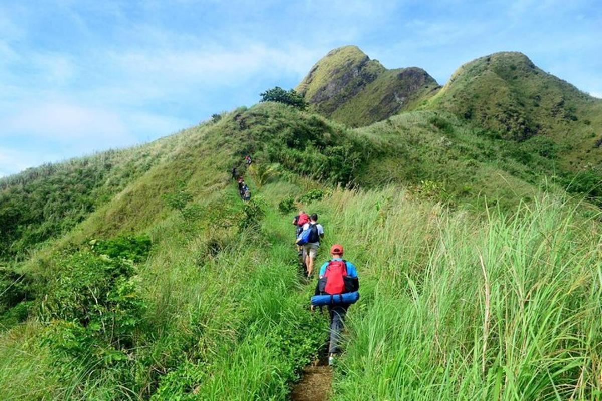 sekelompok orang berjalan menaiki bukit berumput