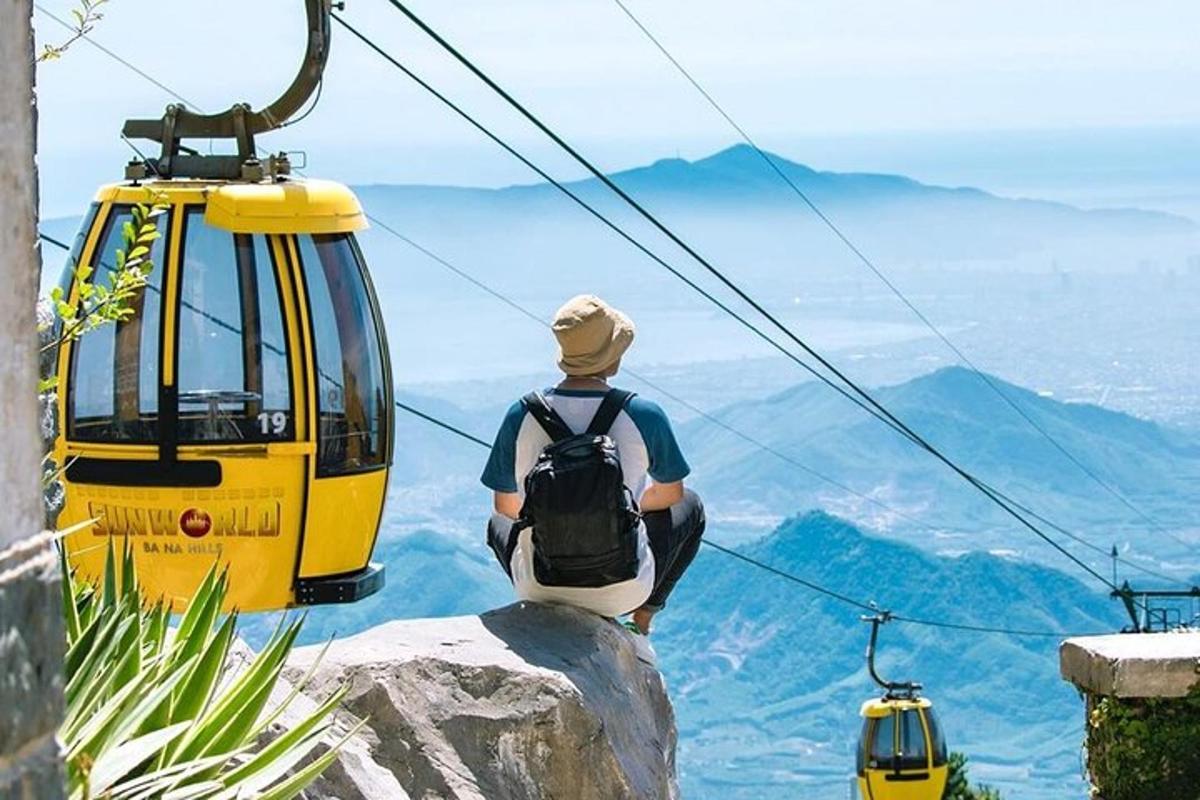 um homem sentado em uma rocha observando um teleférico