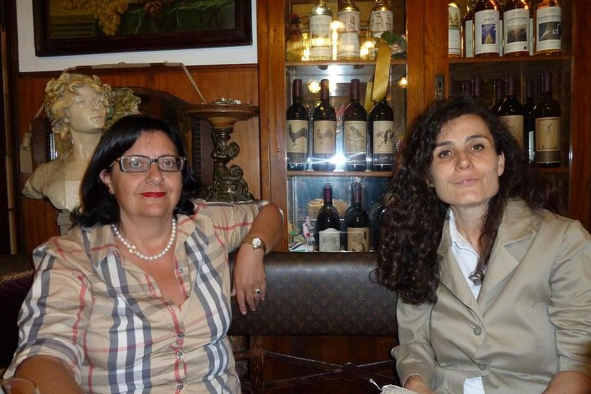 two women sitting in a bar with bottles of wine