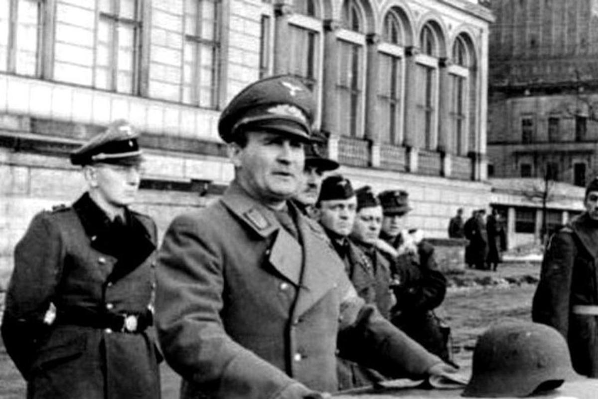 skupina mužov v uniformách stojacich pred budovou