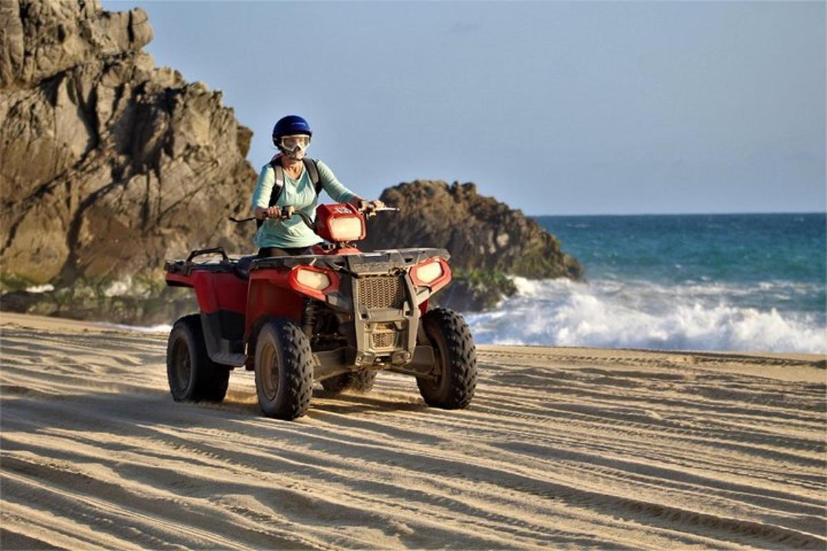 eine Person, die am Strand mit einem Quad fährt