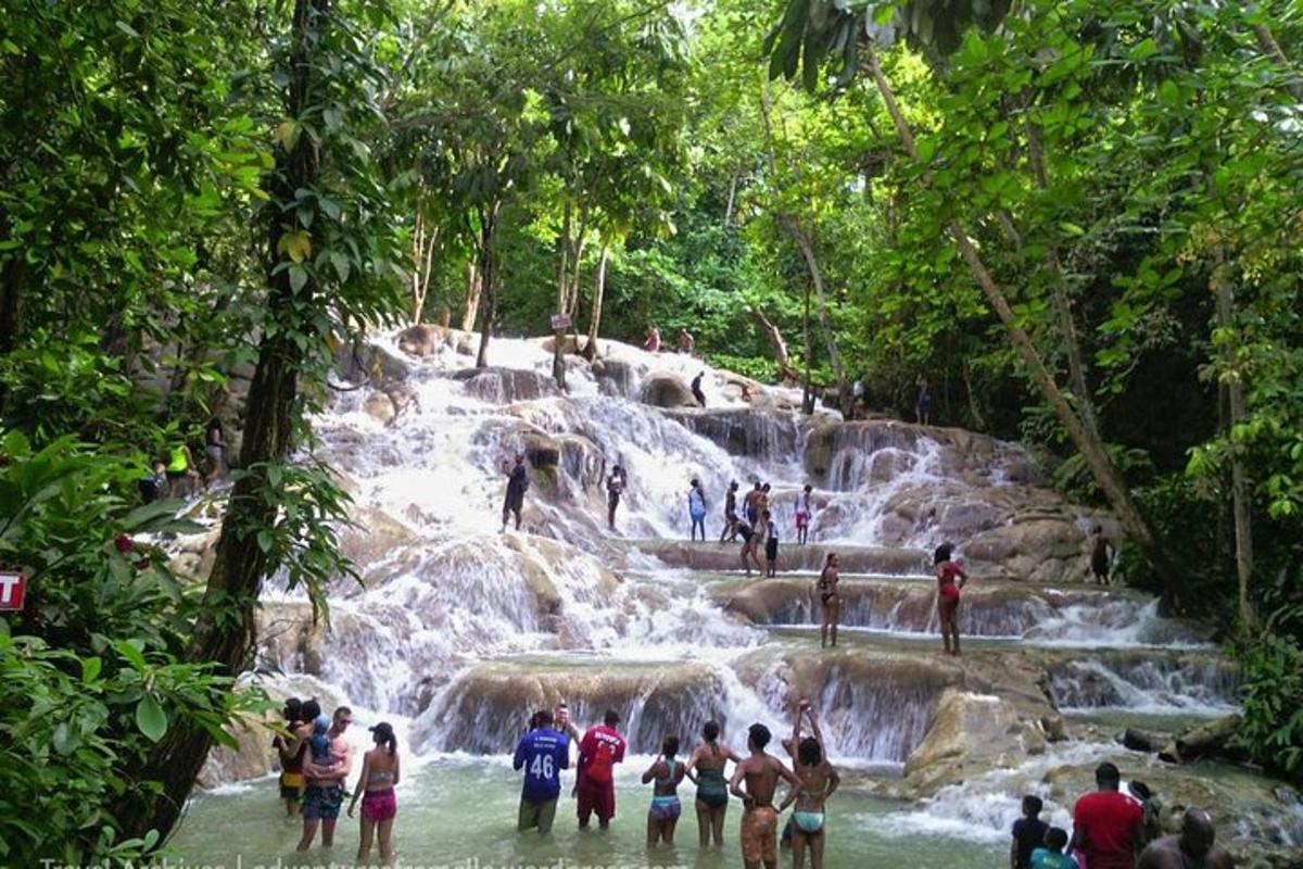 a group of people standing in the water at a waterfall