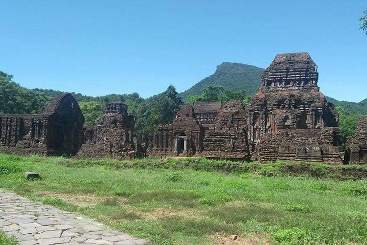 un antico edificio in un campo con le montagne sullo sfondo