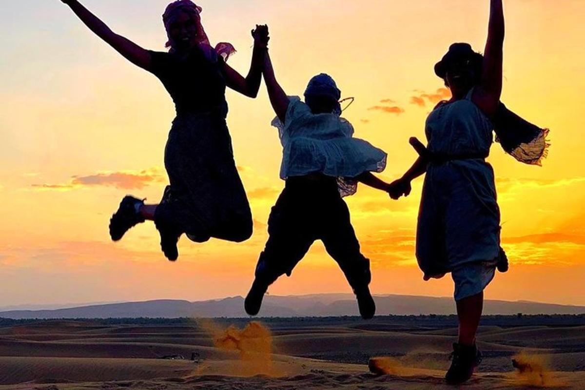 a group of people jumping in the desert at sunset