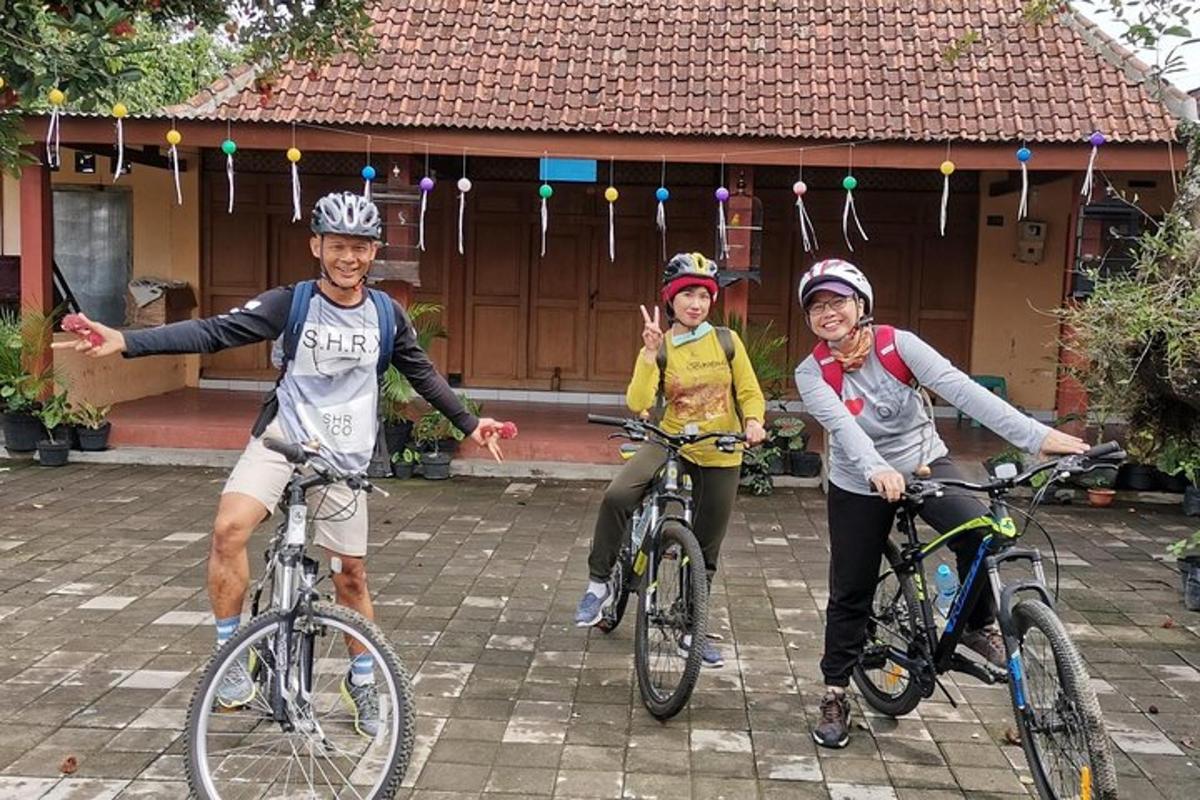 tiga orang mengendarai sepeda di depan sebuah rumah