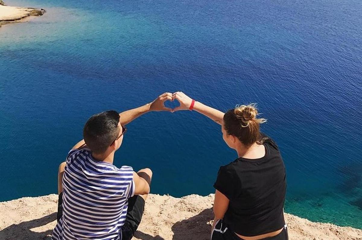 Un hombre y una mujer sentados encima de una roca formando un corazón.