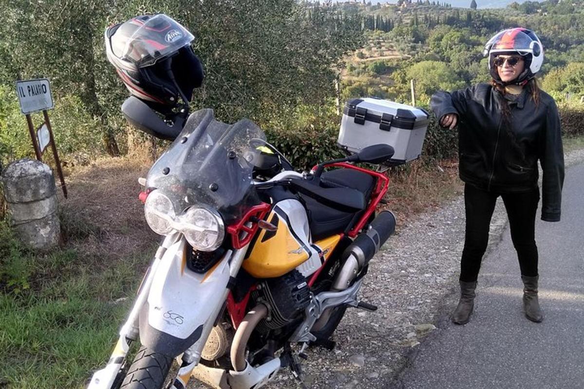 en kvinne som står ved siden av en motorsykkel på siden av en vei