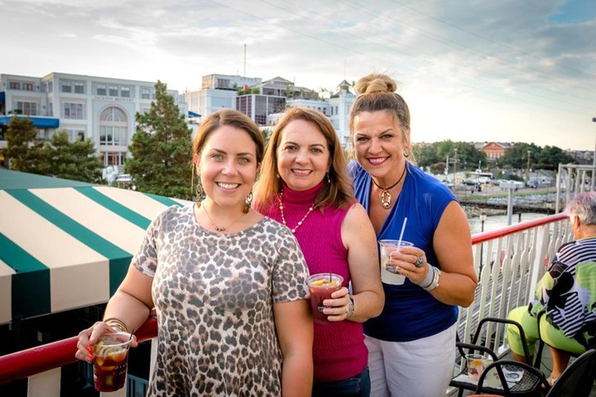 three women standing on a balcony holding drinks
