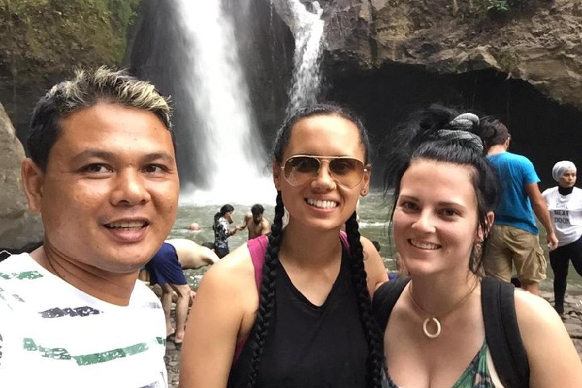 Un grupo de personas de pie frente a una cascada.