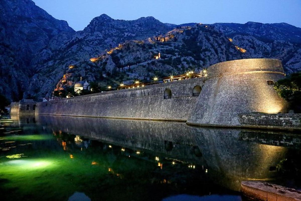 ένας πέτρινος τοίχος δίπλα σε ένα υδάτινο σώμα με βουνά
