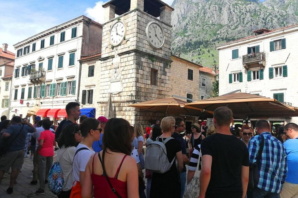 ένα πλήθος ανθρώπων που στέκονται μπροστά από έναν πύργο με ρολόι
