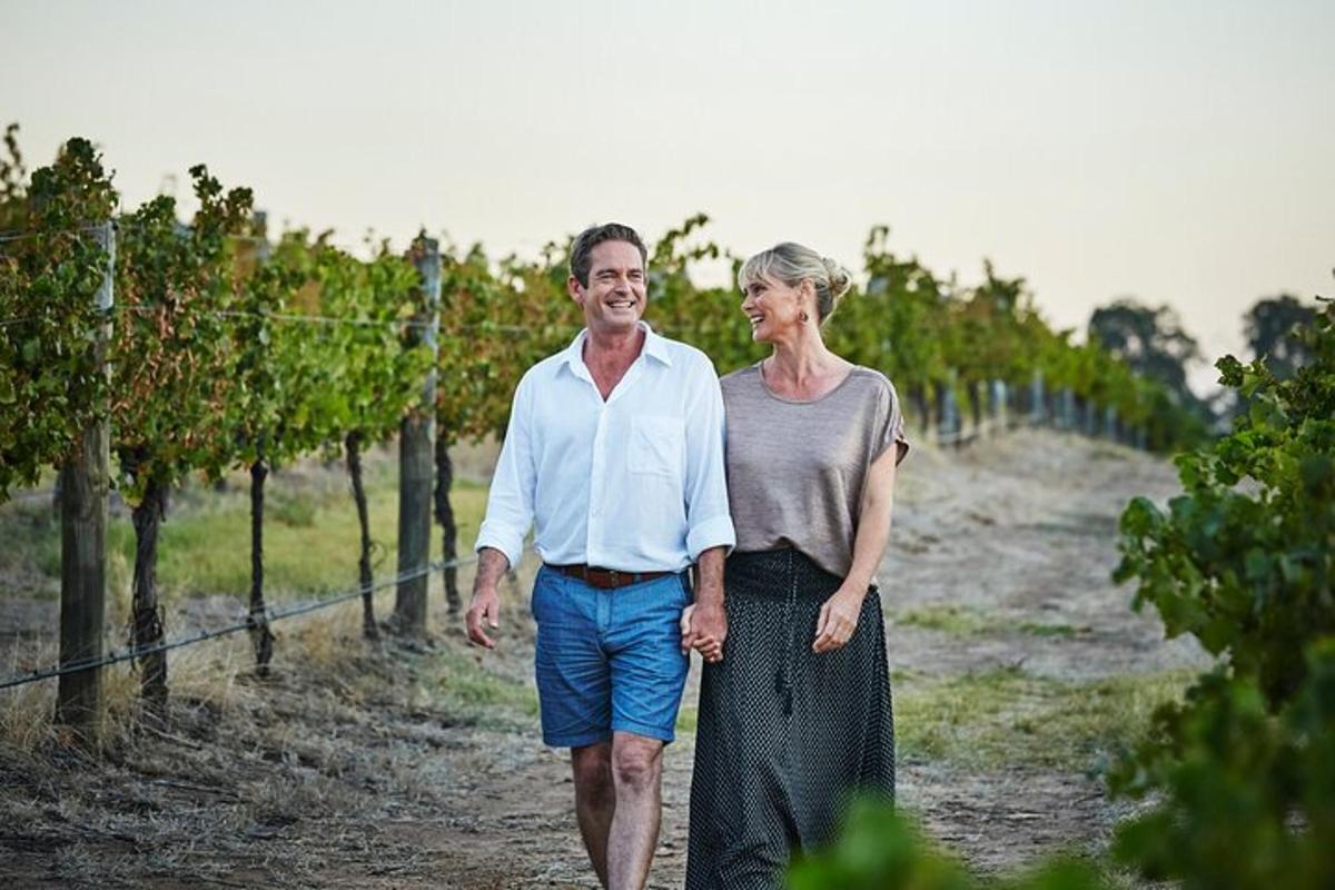 a man and a woman walking through a vineyard