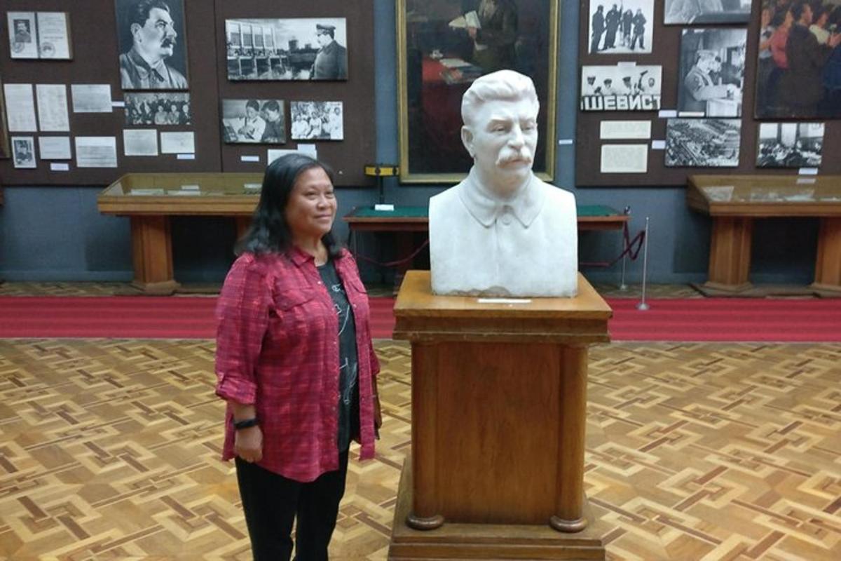 Una mujer parada junto a una estatua de un hombre.
