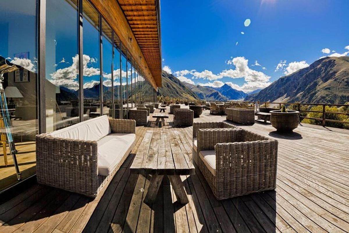 Un patio con sofás y mesas y vista a las montañas.