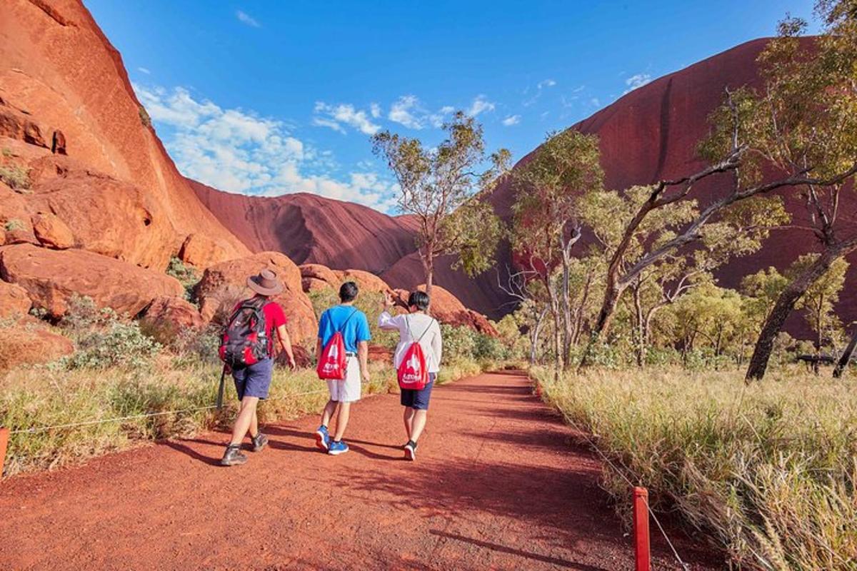 three people walking down a dirt trail in a canyon