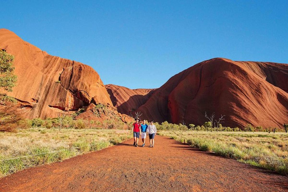 two people walking down a dirt road in ayers rock