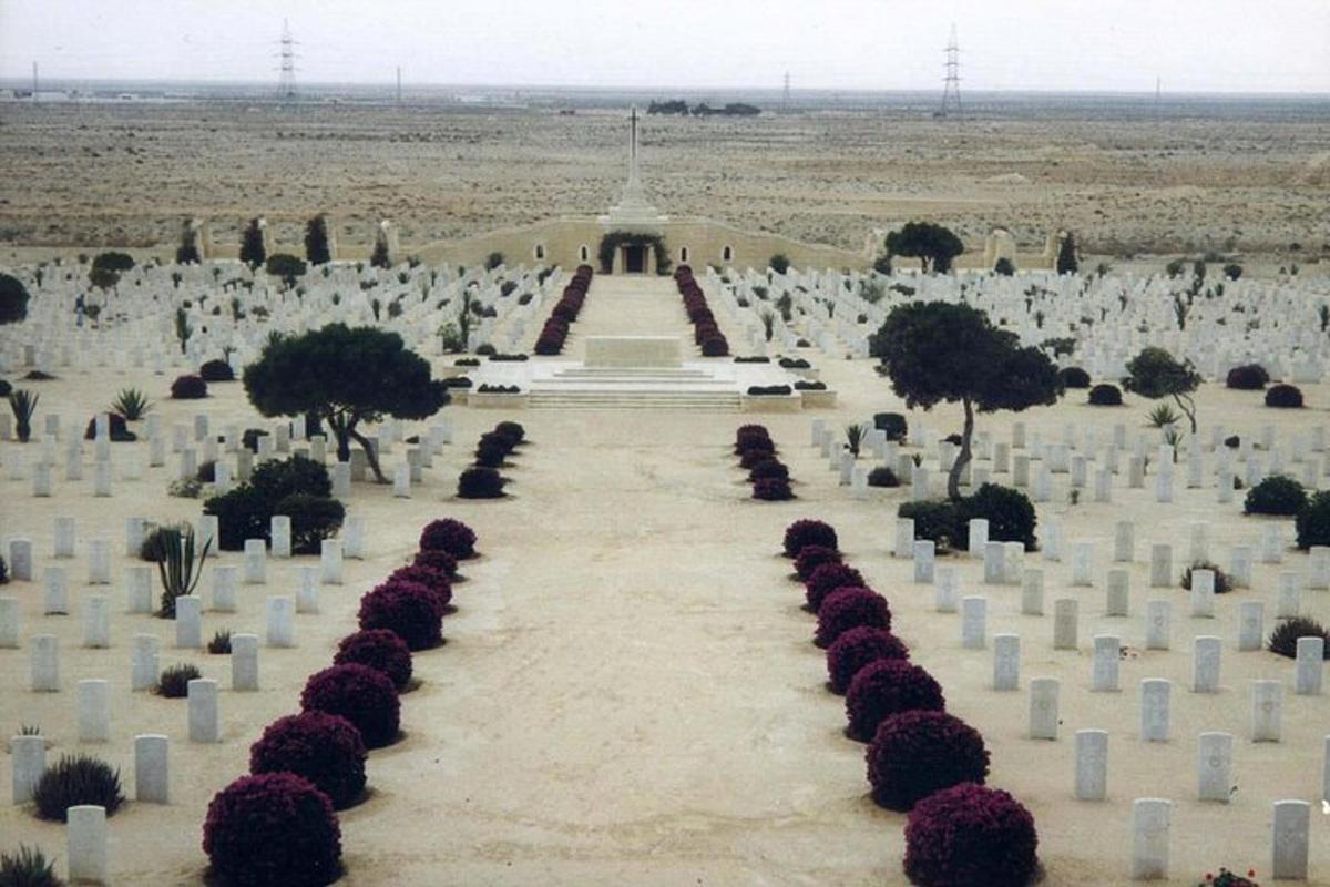 um cemitério com sepulturas brancas e árvores e um edifício