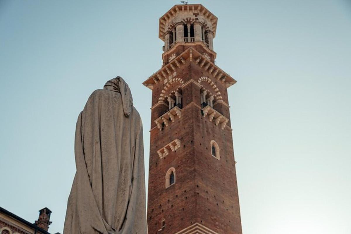 una torre del rellotge alta amb una estàtua al davant