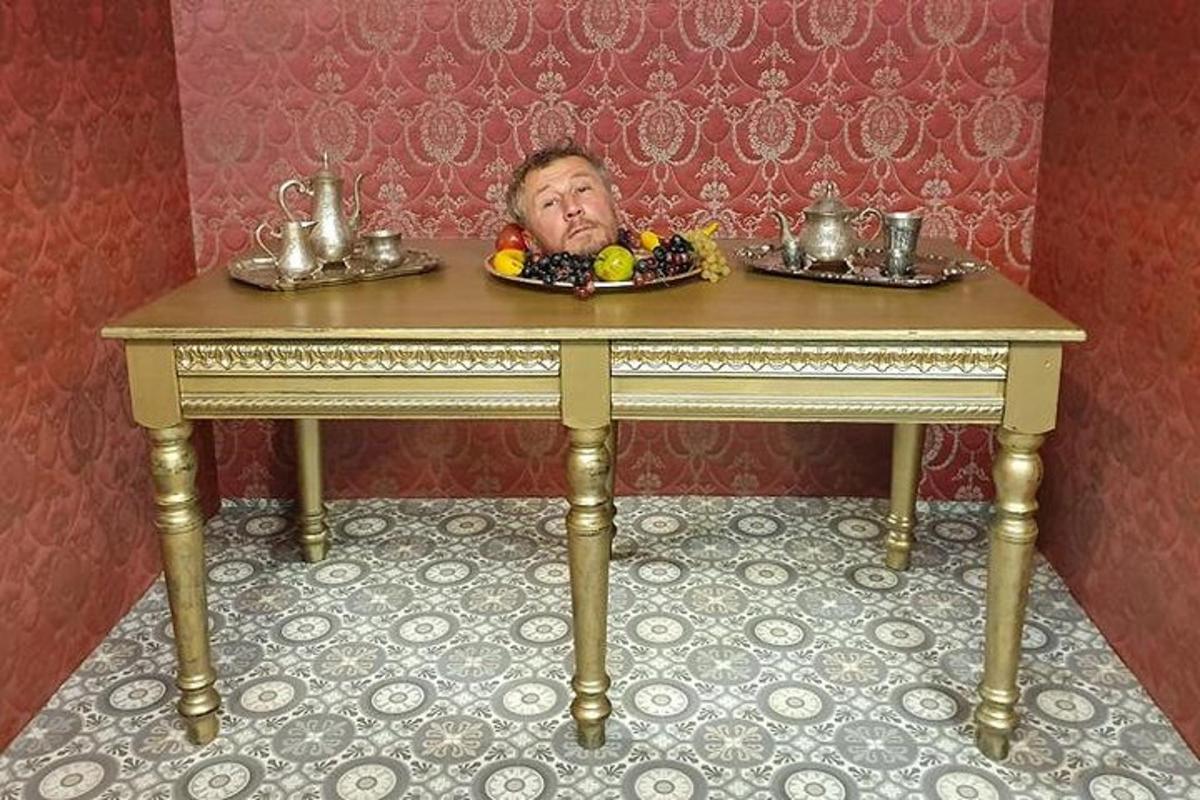 an old man is hiding behind a table