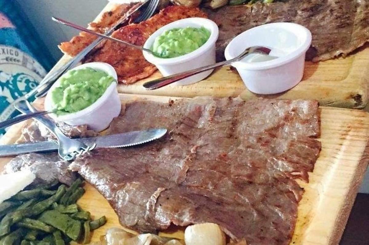 a cutting board with a piece of meat and some dips