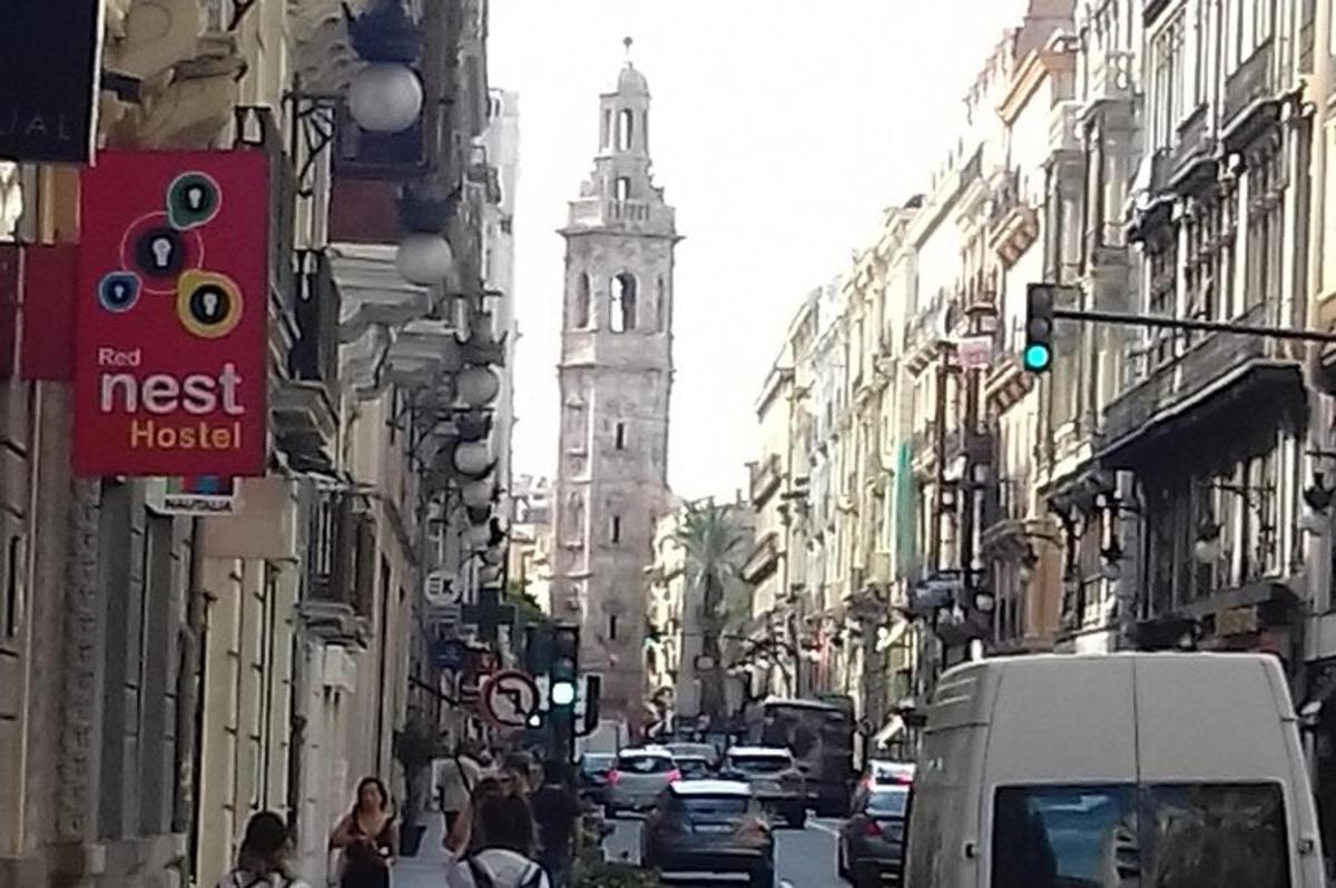 a busy city street with cars and a tall tower