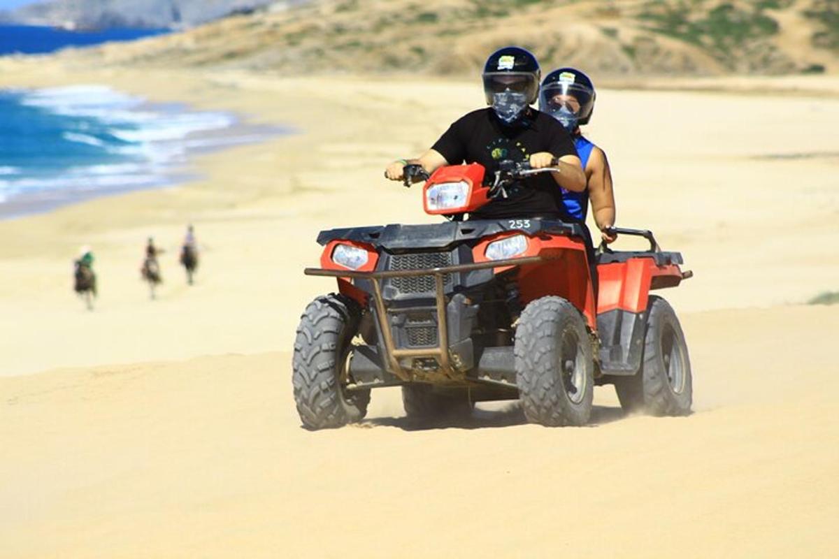 due persone in sella a un quad sulla spiaggia