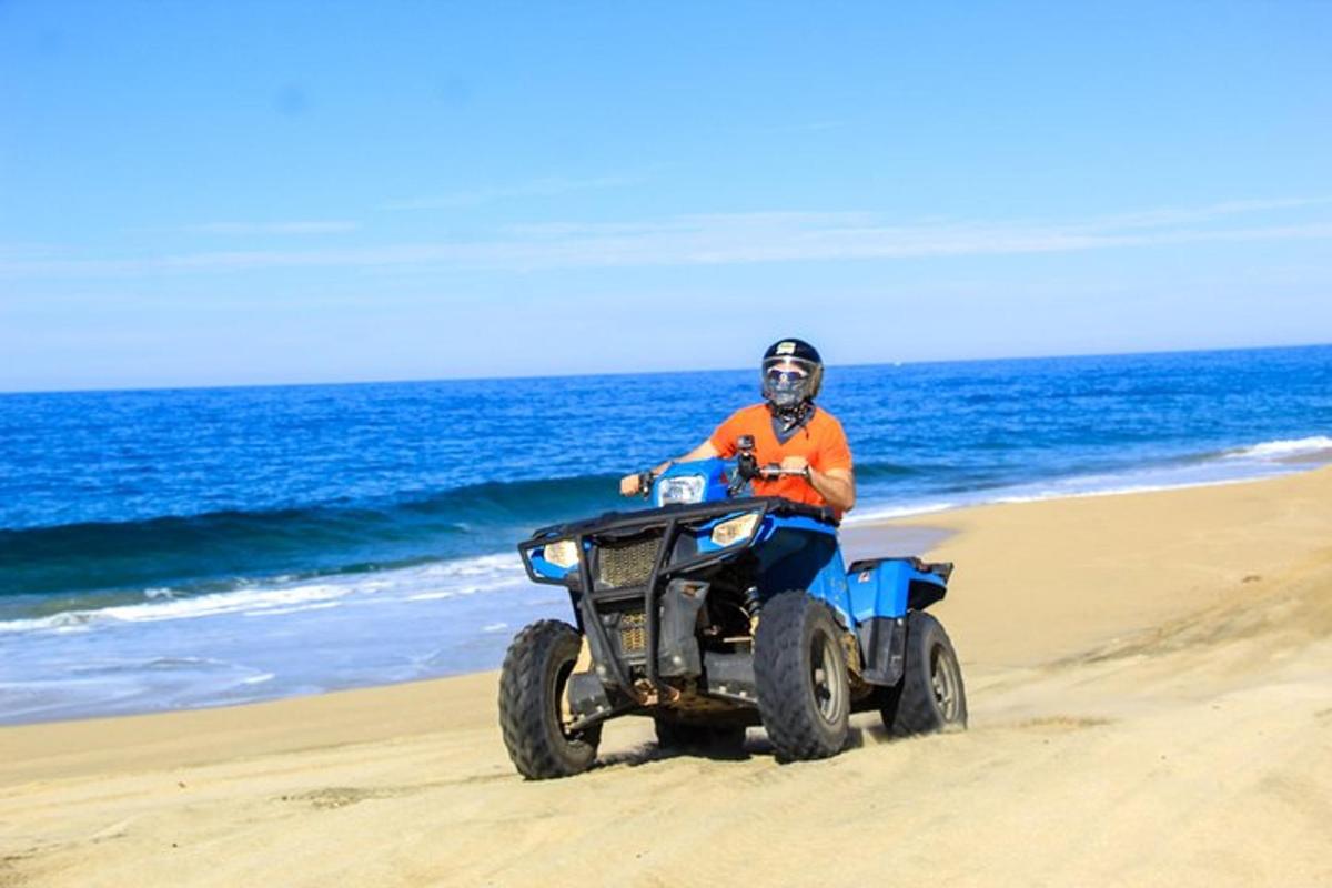 un uomo in sella a un quad sulla spiaggia