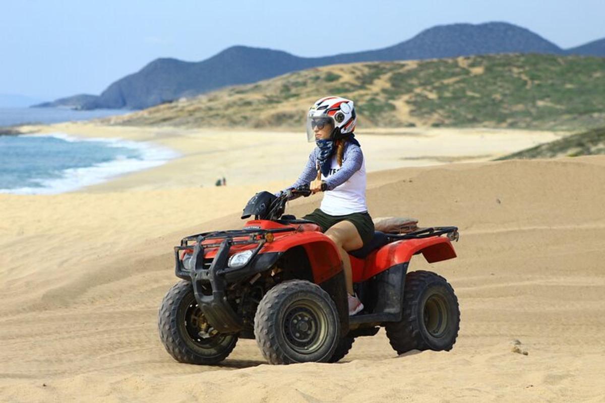 una donna in sella a un quad sulla spiaggia