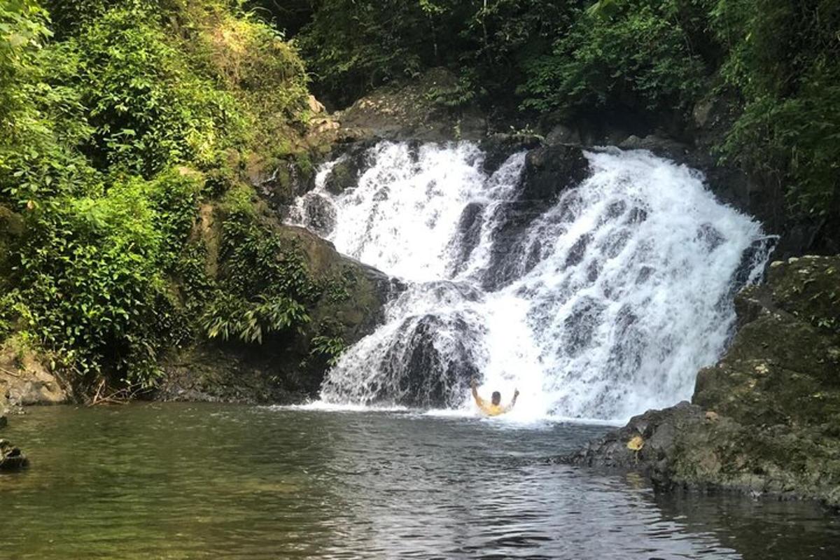 a person in the water in front of a waterfall
