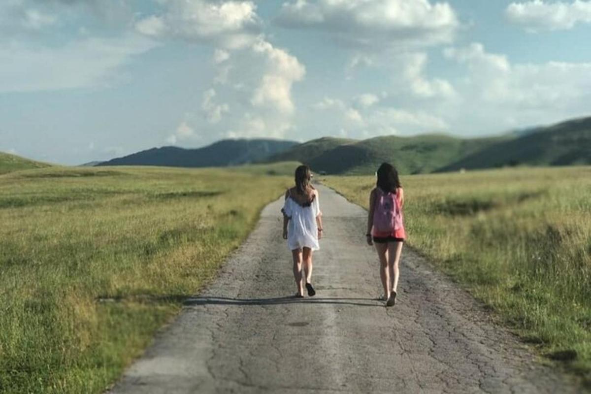 dos chicas caminando por un camino de tierra