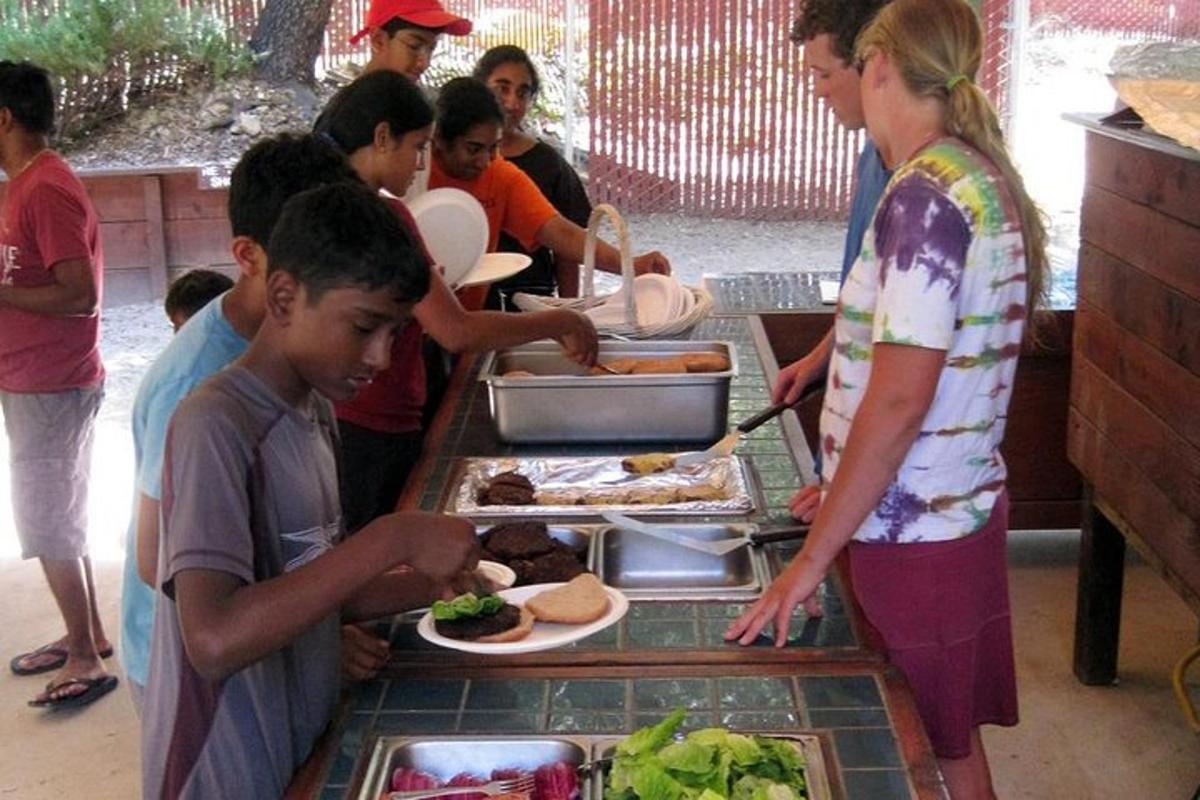 un grup de nens drets al voltant d'una taula amb plats de menjar