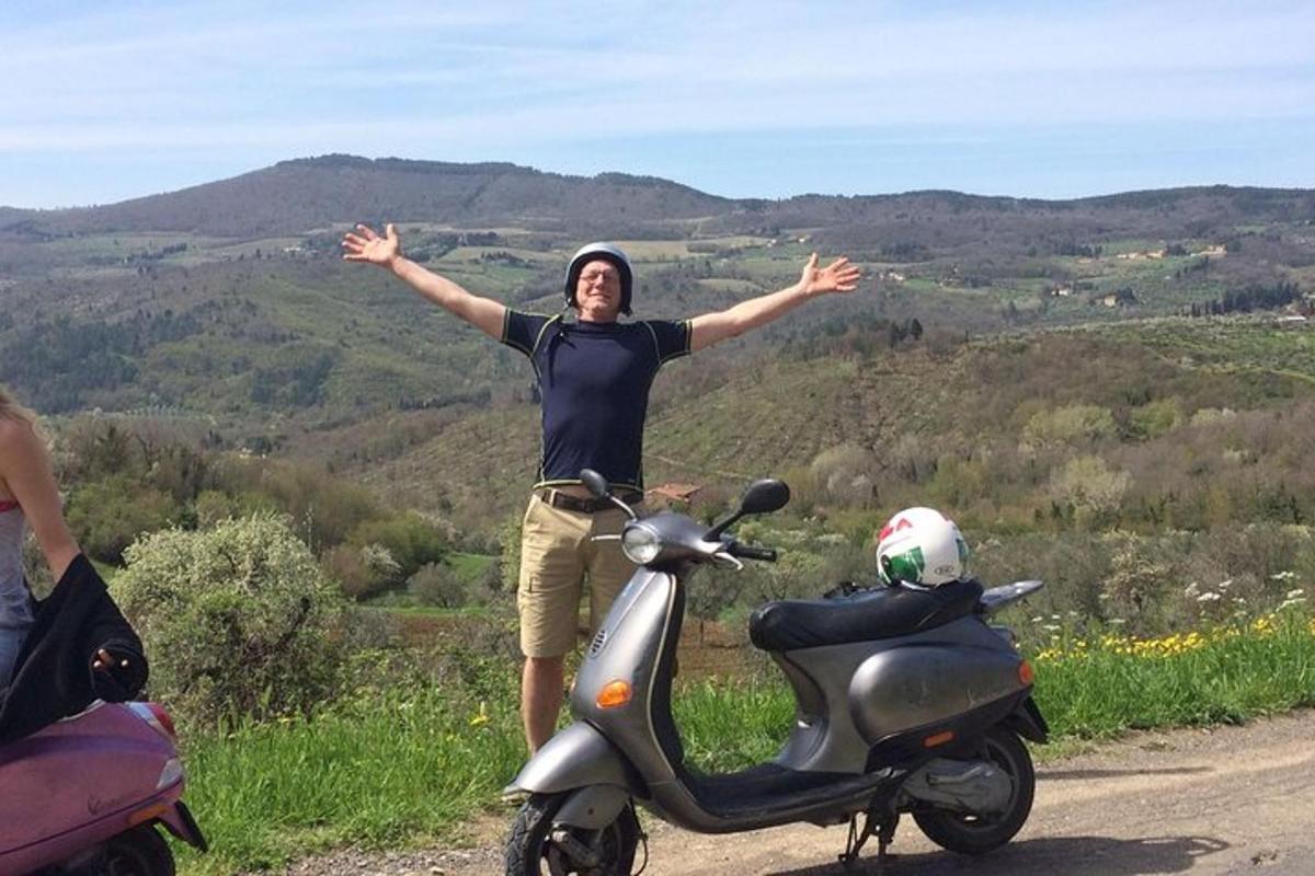 a man standing next to a scooter on a road