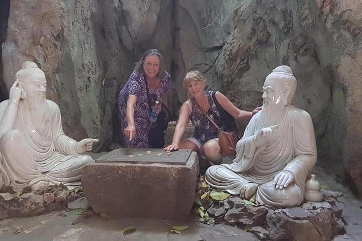 un gruppo di donne sedute accanto a statue in una grotta