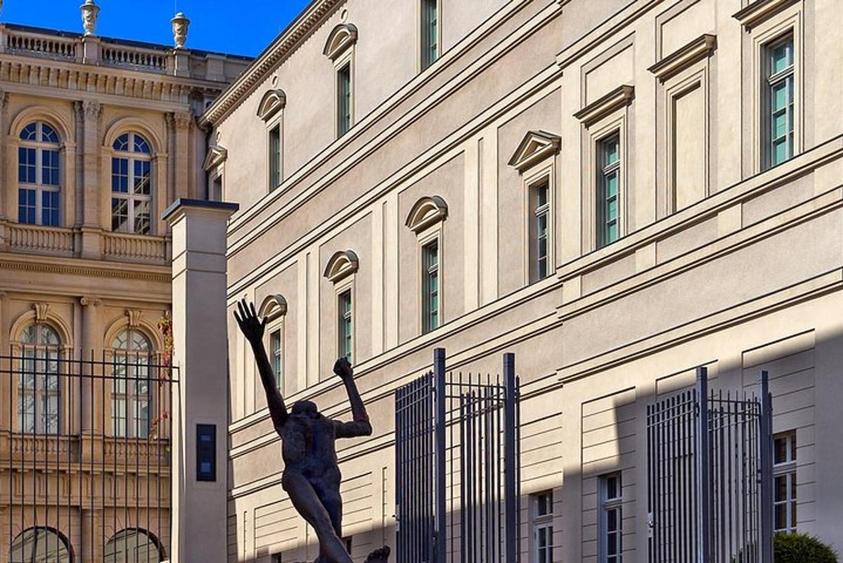 o statuie a unui bărbat care se întinde spre o clădire