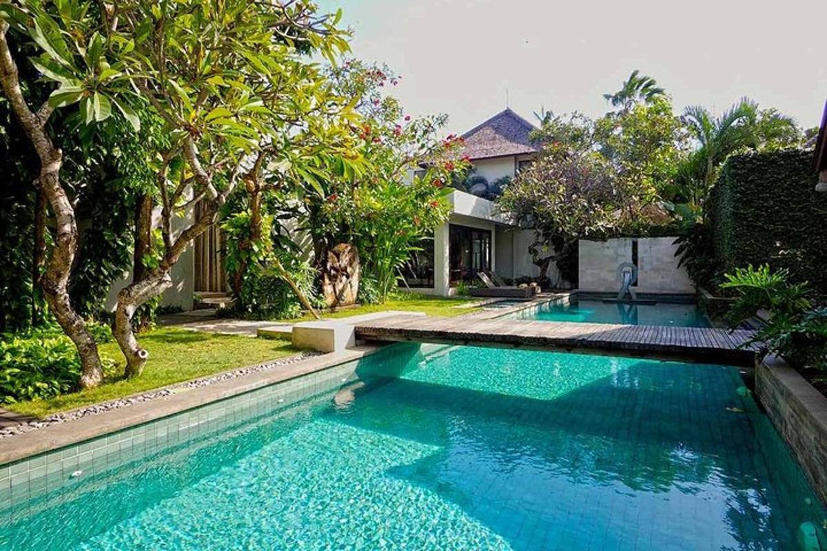 a swimming pool in front of a house with trees