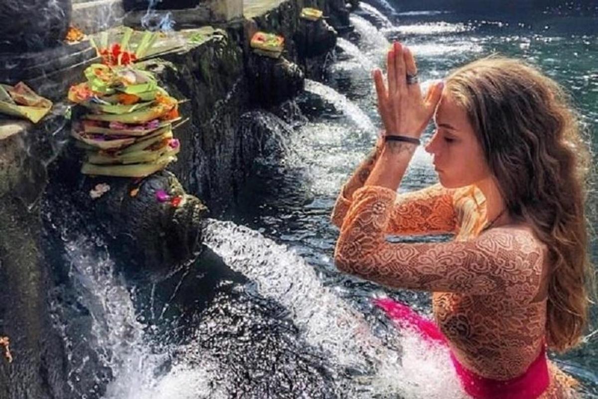 een vrouw die in het water staat bij een waterval